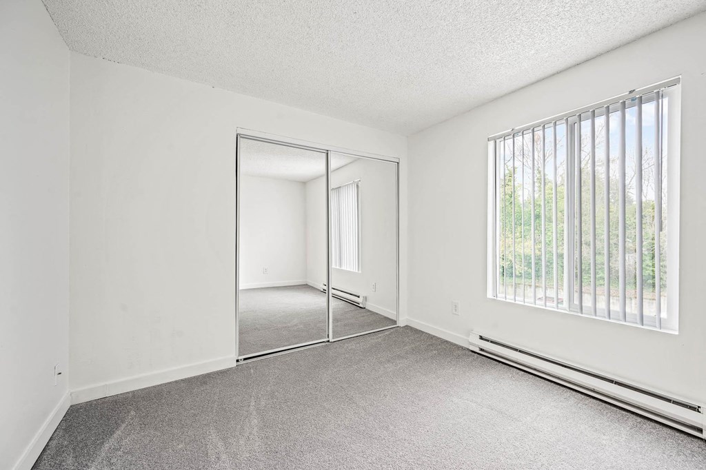 a bedroom with a large window and a mirror