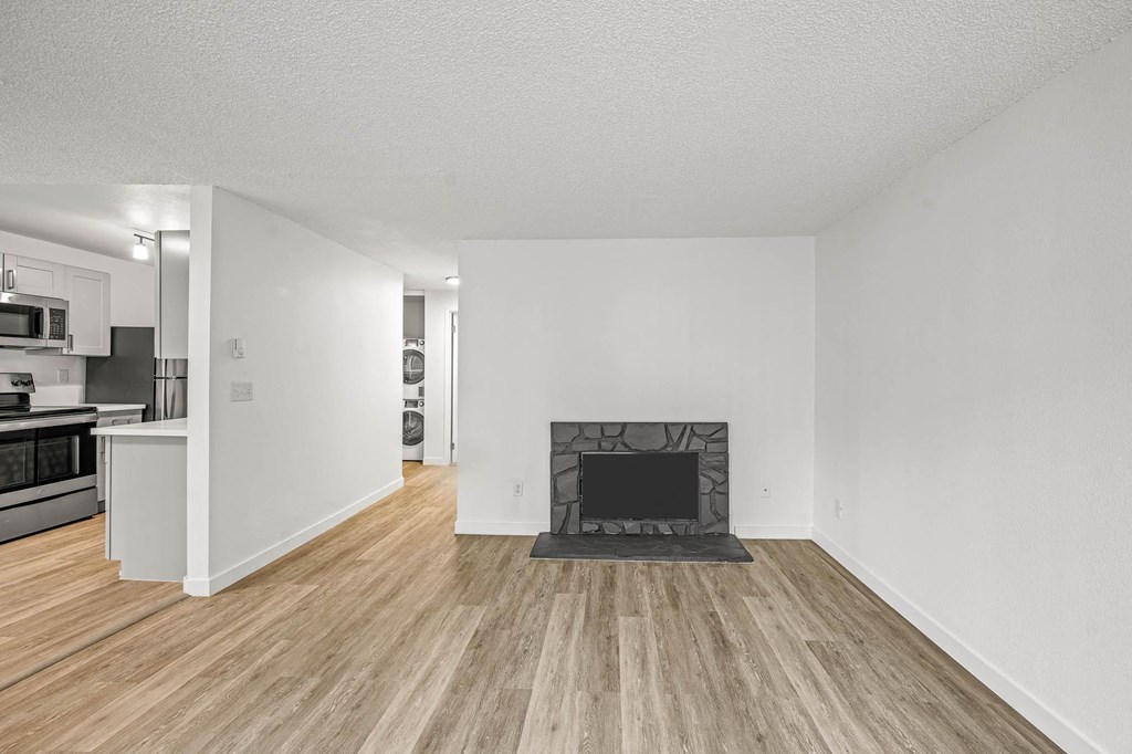 a living room with a fireplace and a kitchen in the background