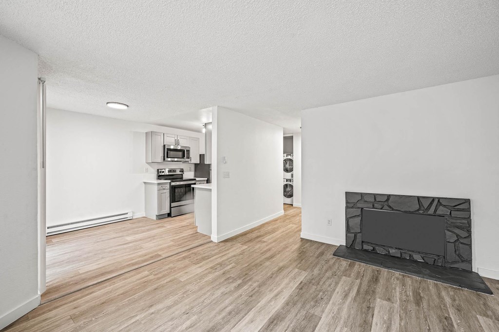 a living room with a fireplace and a kitchen in the background