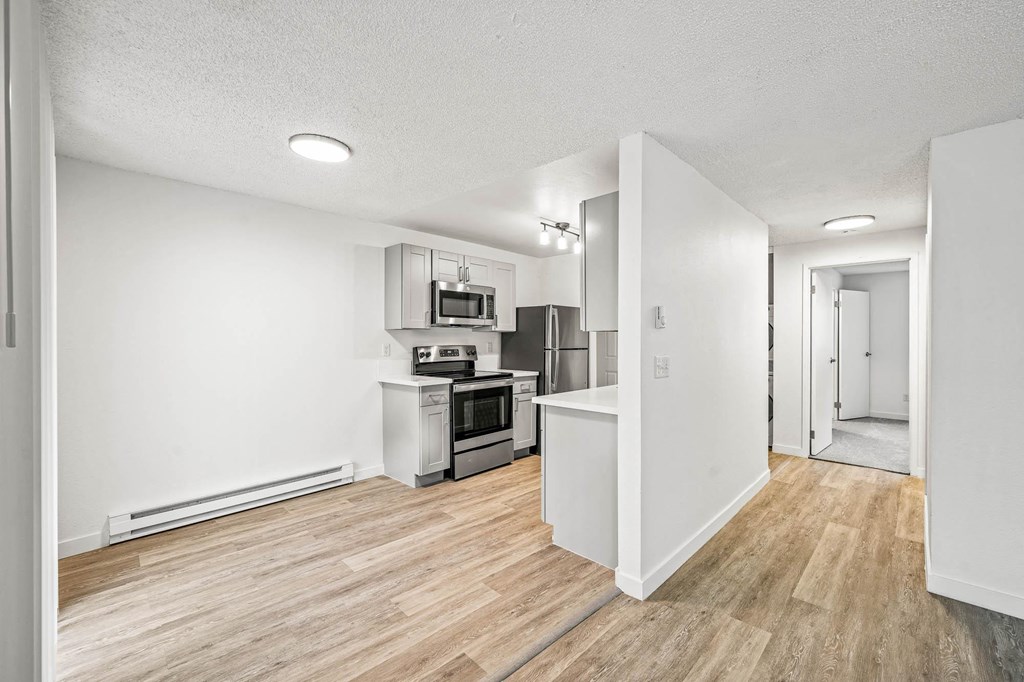 a kitchen and living room with hardwood floors and white walls