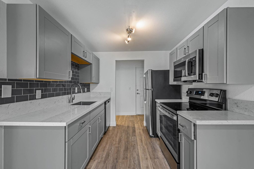 a kitchen with gray cabinets and white countertops