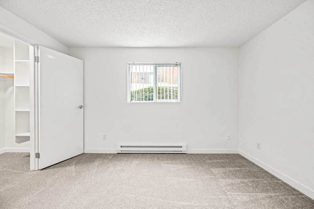 a bedroom with a large window and white walls
