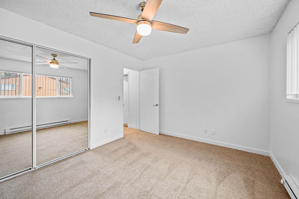 a bedroom with a ceiling fan and a mirror