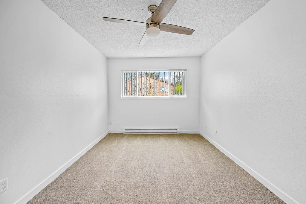 an empty room with a ceiling fan and a window