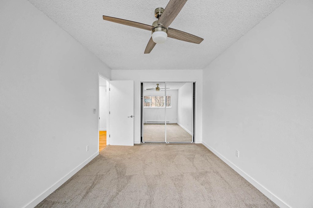 a bedroom with a ceiling fan and a door to a hallway