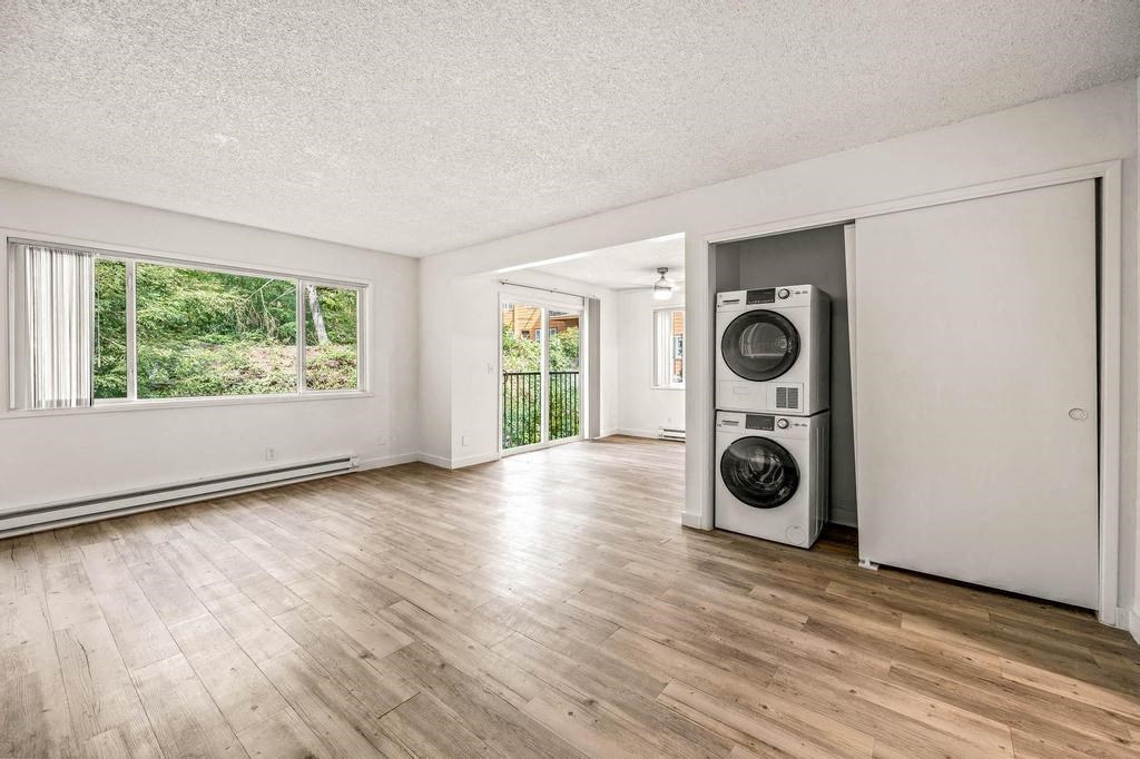 an empty living room with a washer and dryer