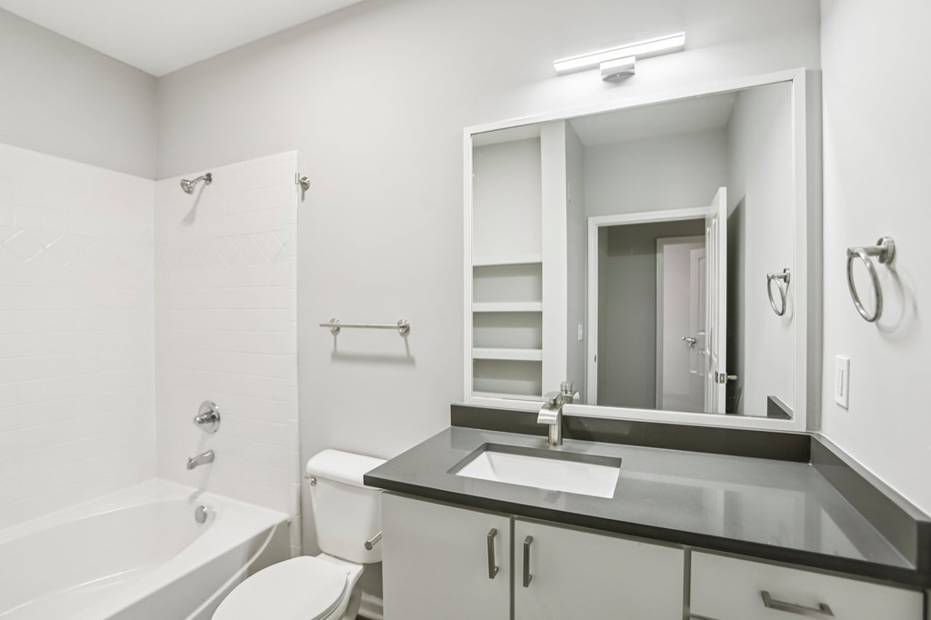 A white bathroom with a black counter top and a white toilet.