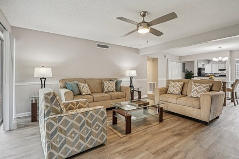 A living room with a beige couch and a glass coffee table.