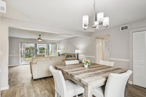A dining room with a wooden table and white chairs.