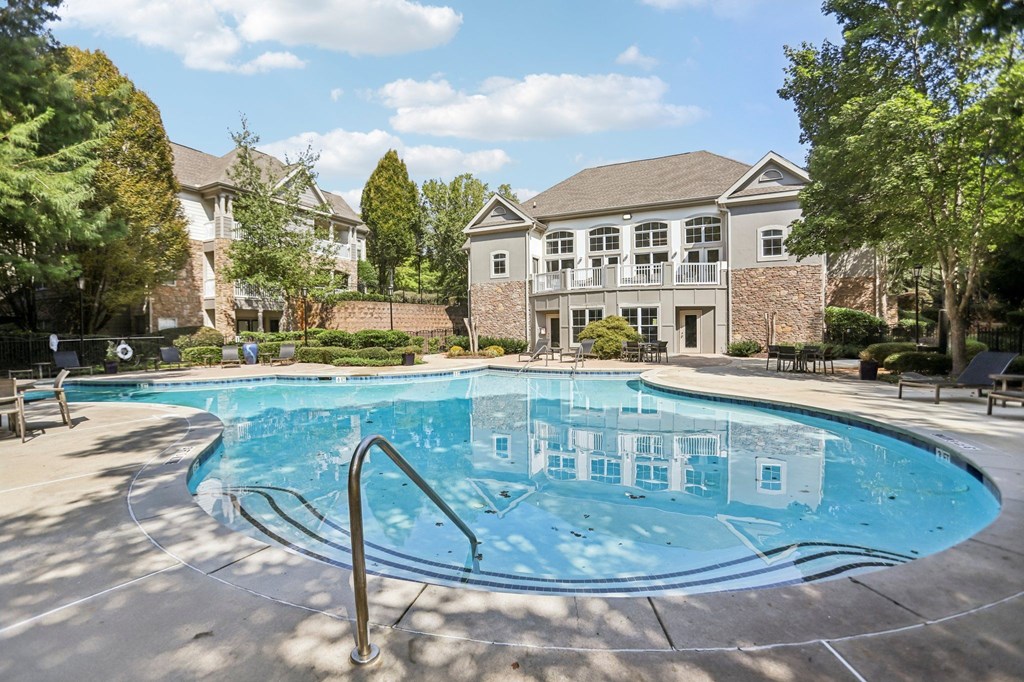 A swimming pool in front of a house with a brick wall.