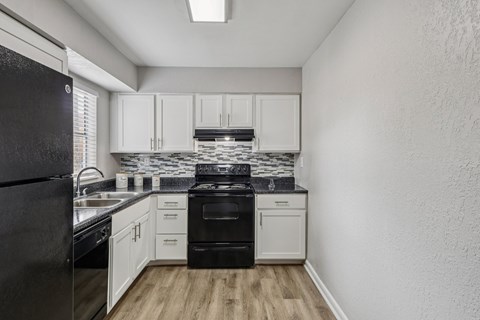 A kitchen with black appliances and white cabinets.