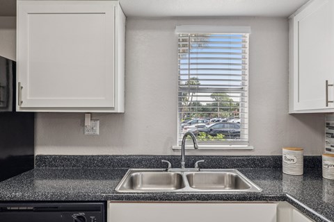 A kitchen with a black dishwasher and a granite countertop.