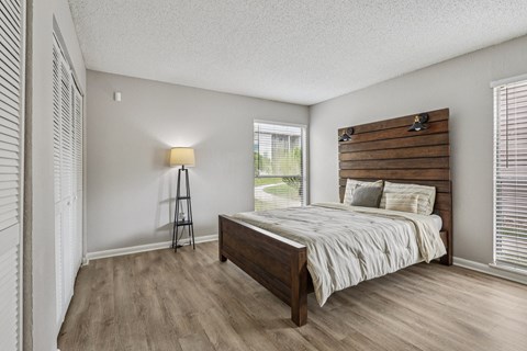 A bedroom with a bed, wooden headboard, and a floor lamp.
