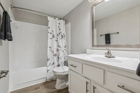 A white toilet with a floral shower curtain in a bathroom.