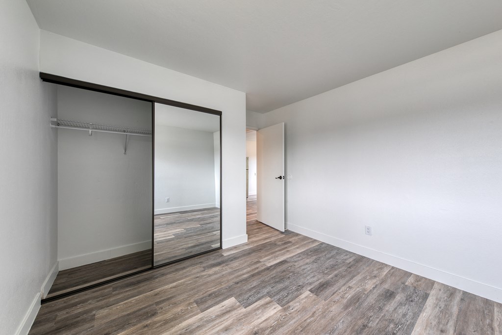 a bedroom with white walls and hardwood floors