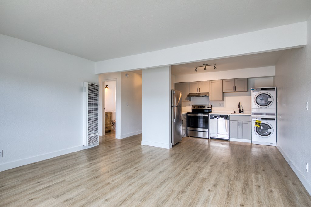 a kitchen and living room with hardwood floors and white walls