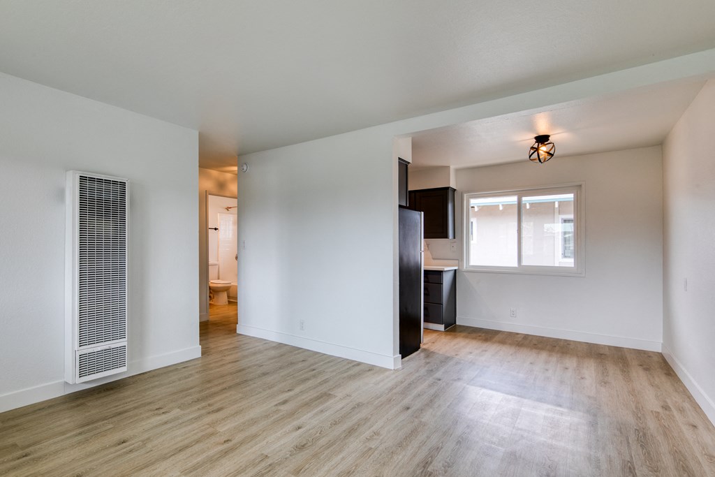 an empty living room with a kitchen in the background