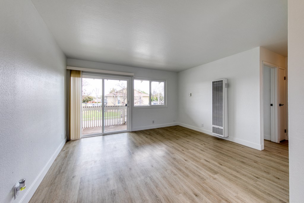 a bedroom with hardwood flooring and a sliding glass door leading to a balcony