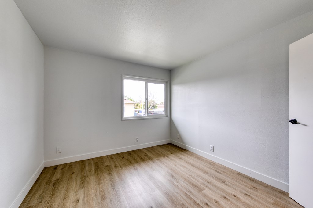 a bedroom with hardwood floors and a window