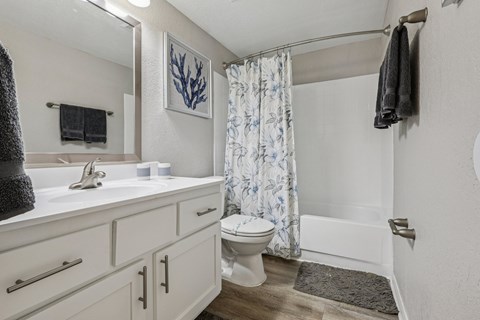 A white bathroom with a toilet, sink, and shower.