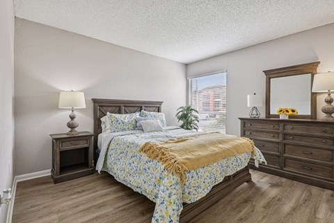 A bedroom with a bed, nightstand, and dresser.