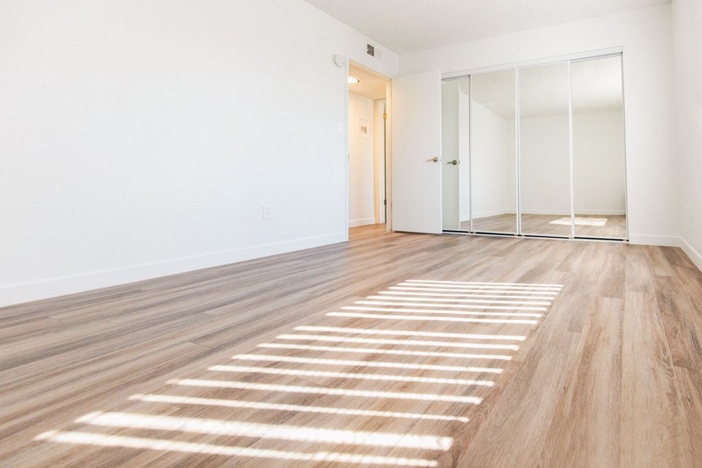a bedroom with white walls and hardwood floors