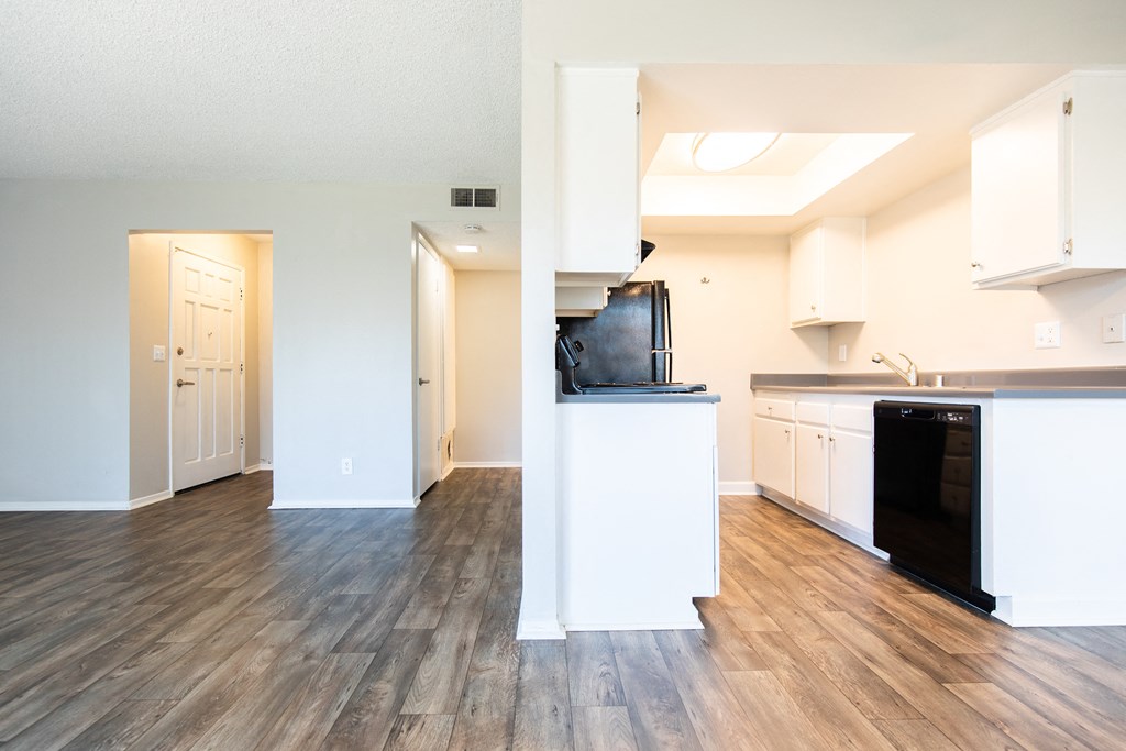 a kitchen and living room with hardwood floors and white walls