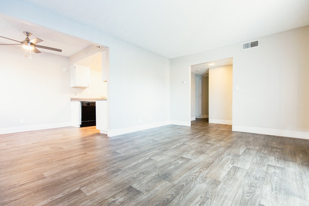 an empty living room with hardwood floors and a ceiling fan