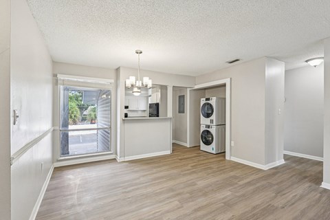 A room with a window, a chandelier, and a washer and dryer.