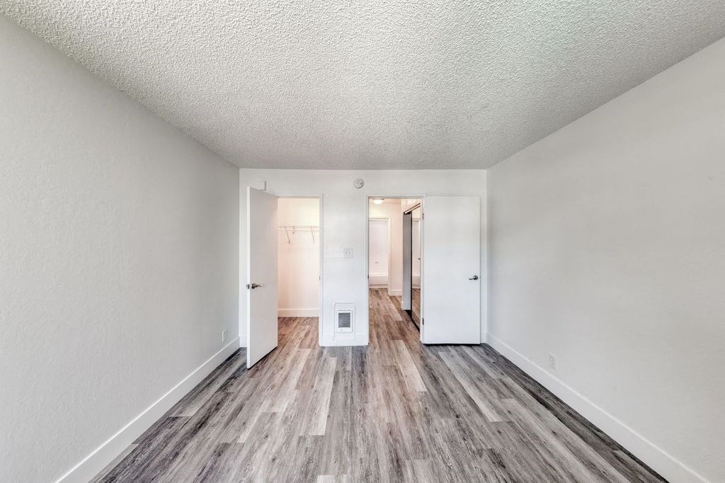 a bedroom with hardwood floors and white walls