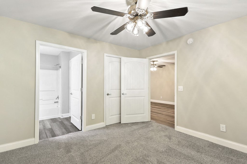 a bedroom with a ceiling fan and a door to a bathroom