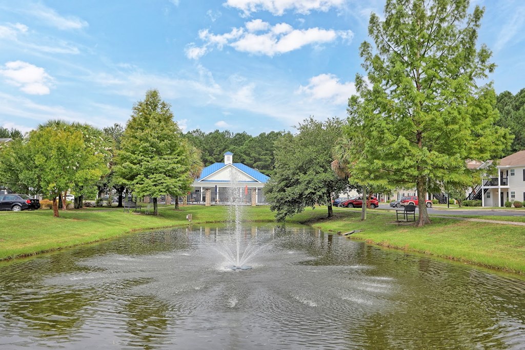 a fountain in a pond with a building in the background