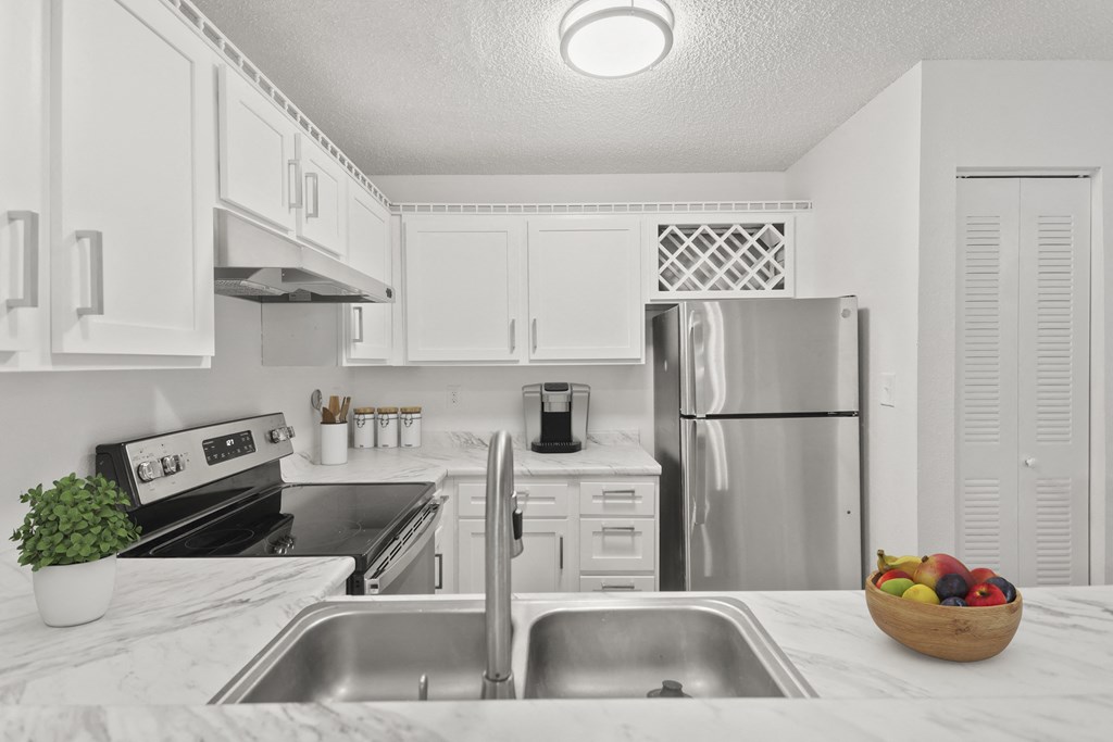 a white kitchen with stainless steel appliances and white cabinets