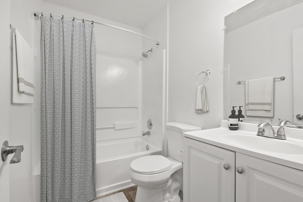 a white bathroom with a shower toilet and sink