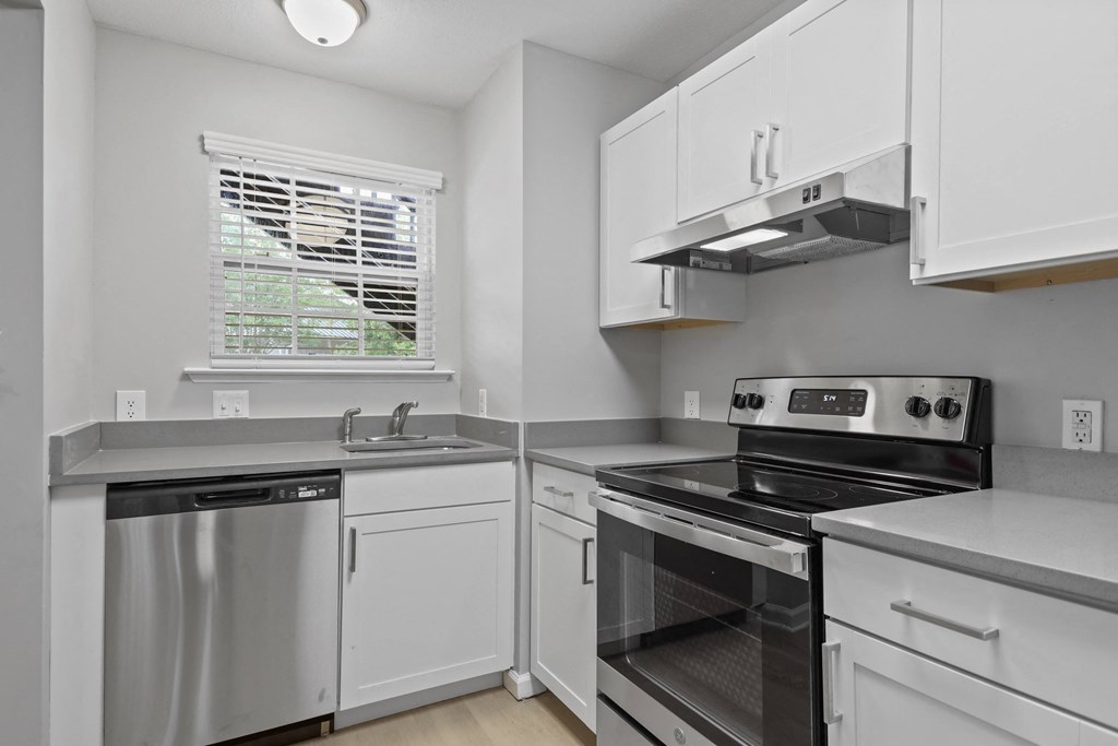 an empty kitchen with white cabinets and stainless steel appliances