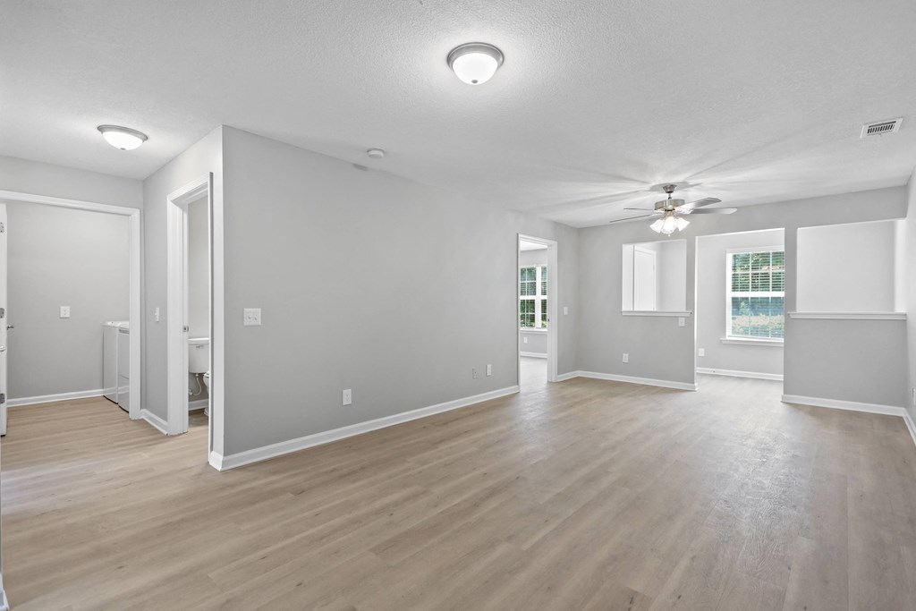 the living room and dining room of an empty house with a ceiling fan
