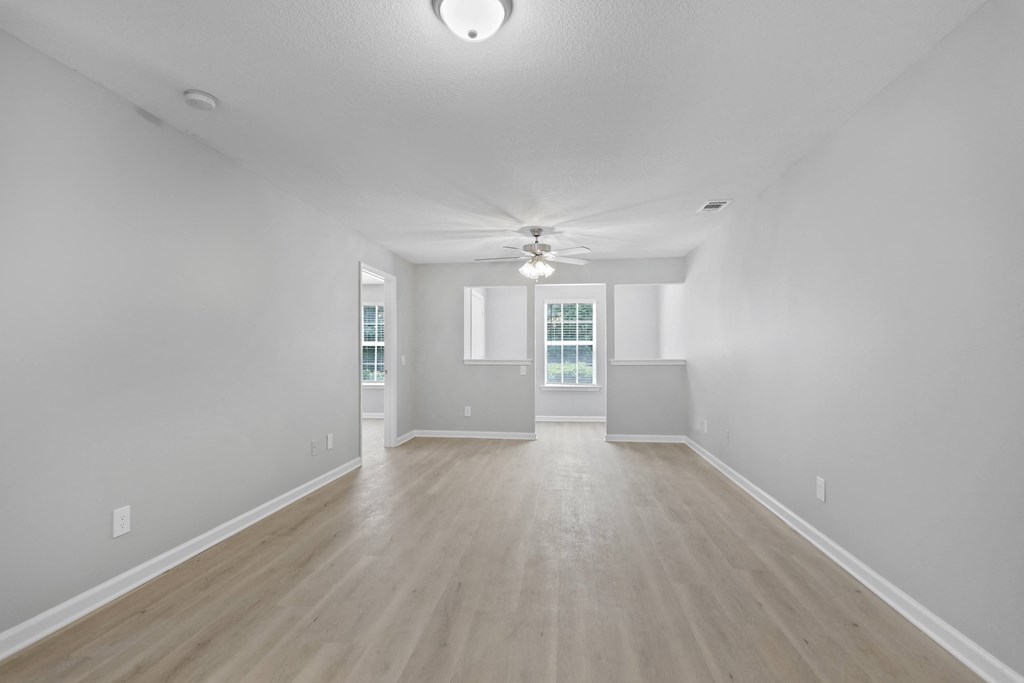 an empty living room with white walls and a ceiling fan