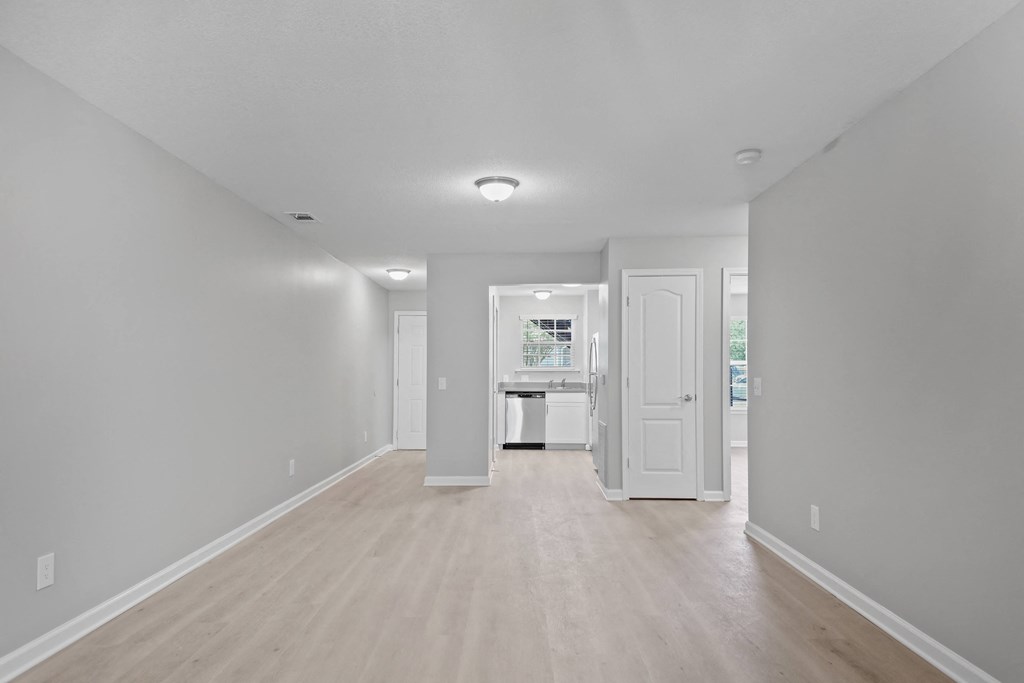 a renovated living room and kitchen with white walls and wood floors