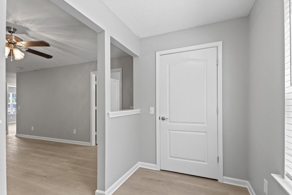 an empty room with a white door and a ceiling fan