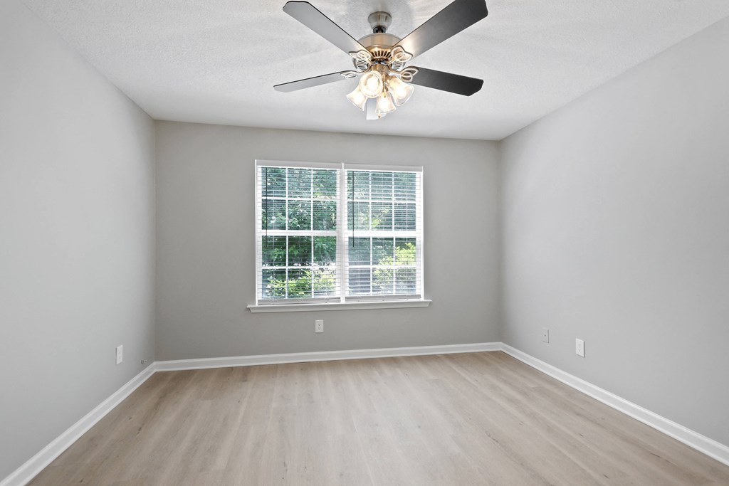 an empty room with a ceiling fan and a window