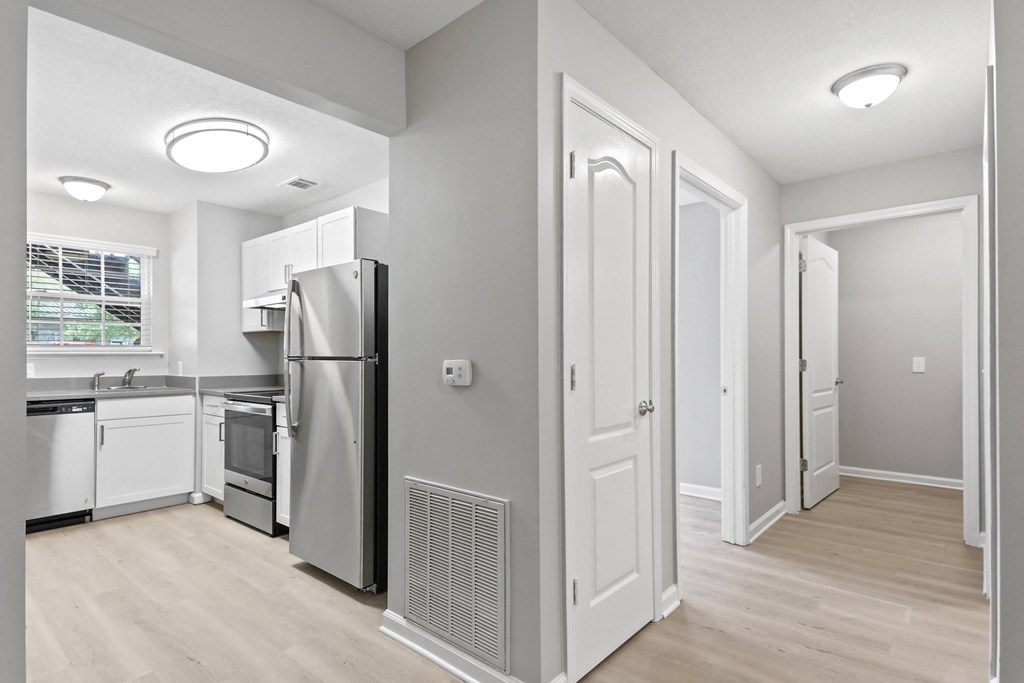 a renovated kitchen with white cabinets and a stainless steel refrigerator