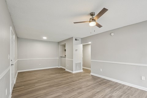 A room with a ceiling fan and wooden flooring.
