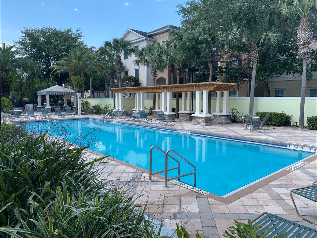 a large swimming pool with a gazebo and palm trees in the background