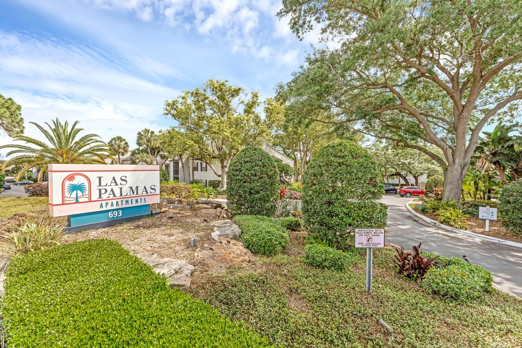 a sign for the las palmas resort sign in front of a road and trees