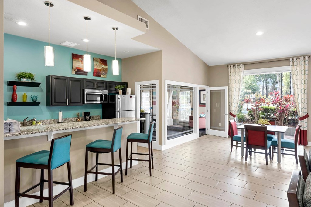 a kitchen with a bar and a dining area with chairs