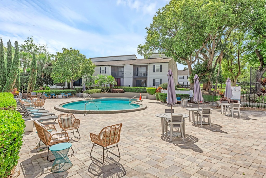 a patio with tables and chairs and a swimming pool