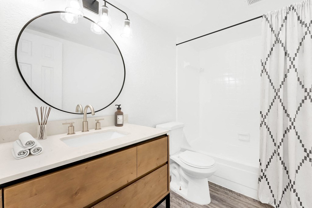 a bathroom with white walls and a wooden vanity with a white countertop
