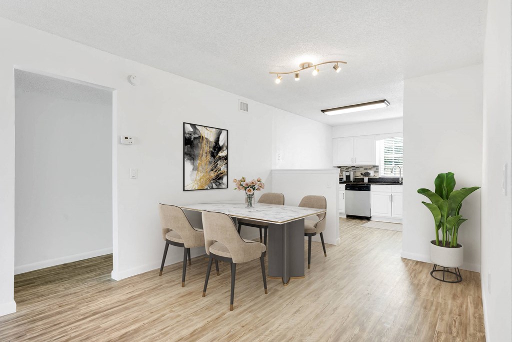 a dining area with a table and chairs and a kitchen in the background