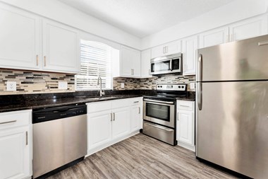 a kitchen with white cabinets and stainless steel appliances