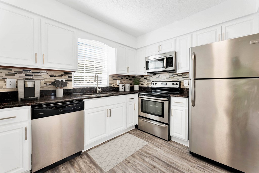 a kitchen with white cabinets and stainless steel appliances